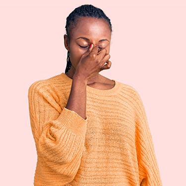 A woman rubs her nose because of sinusitis, an inflammation that usually comes from a cold.