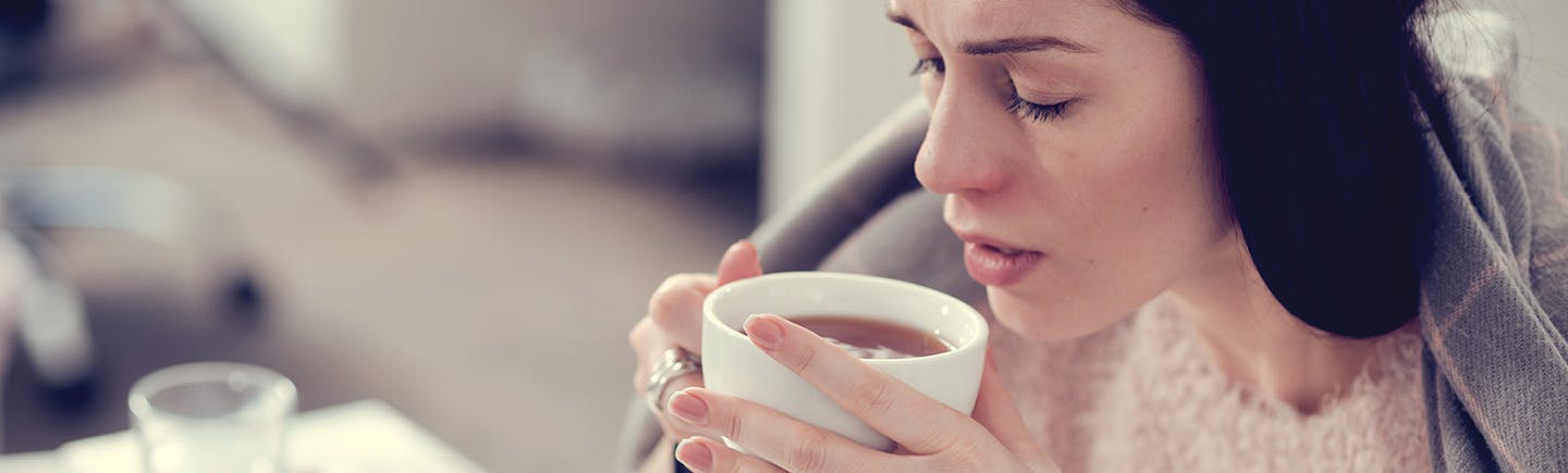Vrouw drinkt een heerlijke kop thee nadat zij haar Otrivine neusspray heeft gebruikt.