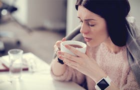 Une femme boit une délicieuse tasse de thé après avoir utilisé son vaporisateur nasal Otrivine.