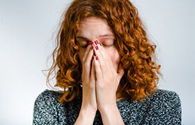 Vrouw van middelbare leeftijd snuit haar neus in verband met een verkoudheid.