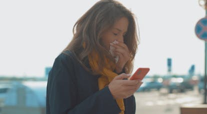 Ragazza con il telefono in mano che si soffia il naso - Rinazina