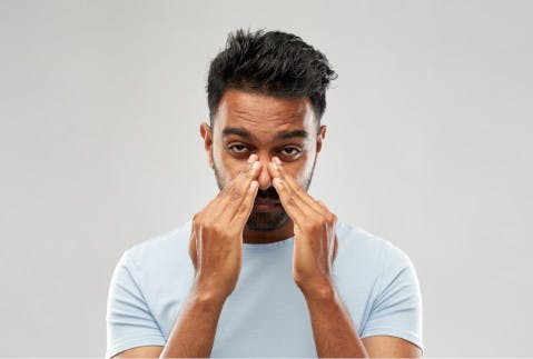 Ragazzo che si tiene il naso per i sintomi della sinusite - Rinazina