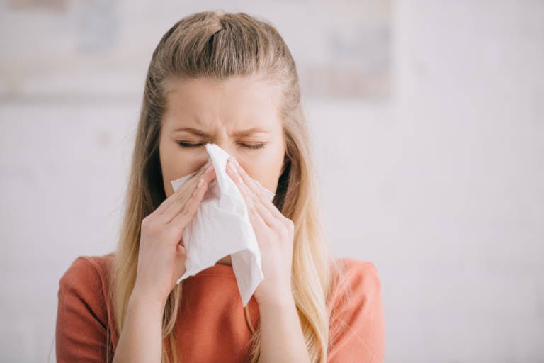 Ragazza che soffia il naso a causa della rinite da allergia al polline - Rinazina