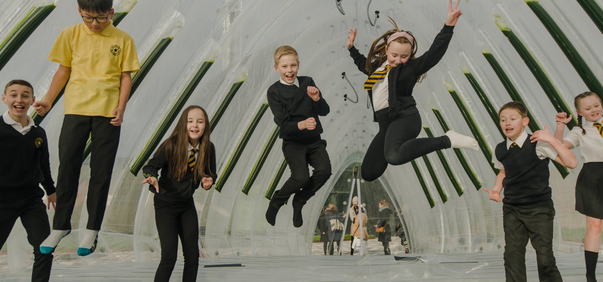 Happy children in school uniform jumping. Text: let's help children breathe cleaner. 