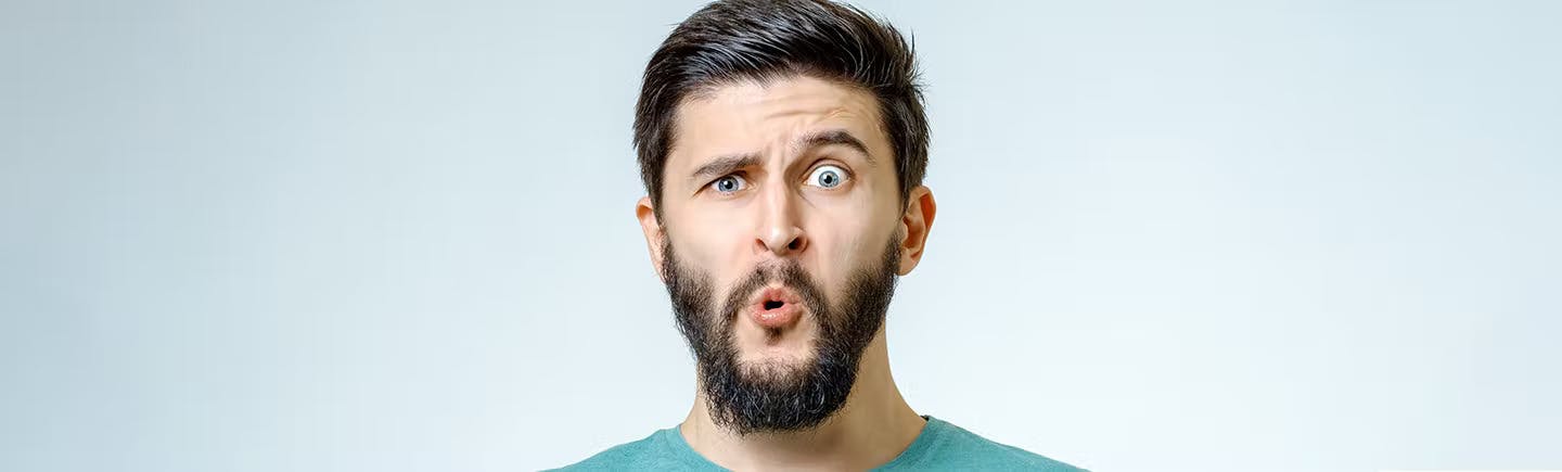 Mann med mørkt hår og skjegg med et overrasket uttrykk etter å lært forskjell på allergi og forkjølelse