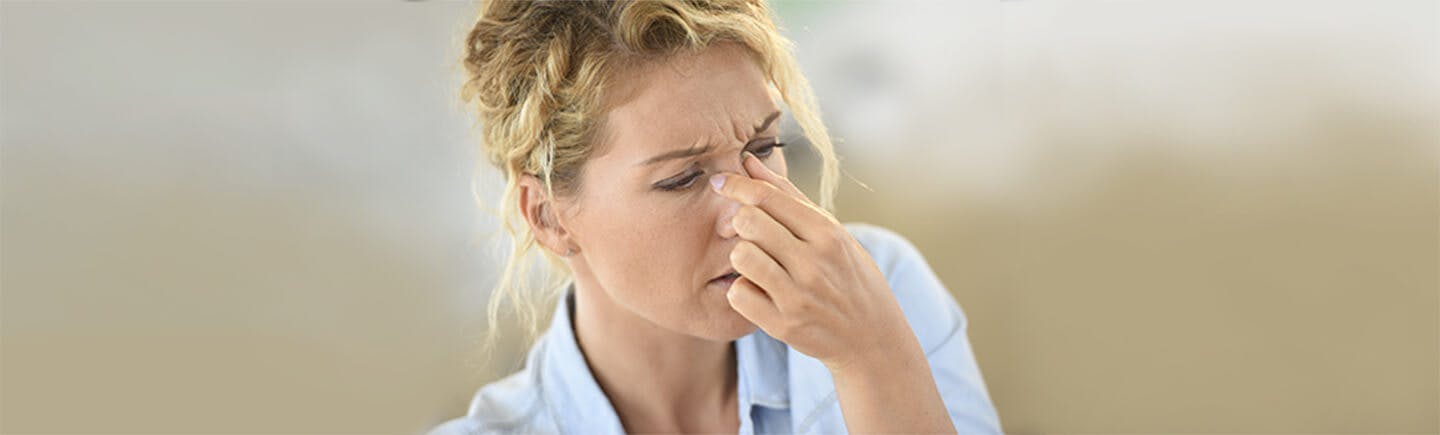 Kvinne med pollenallergi som holder seg på nesen for ikke å nyse: Bli kvitt symptomene med Otrivin allergi nesespray