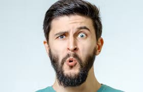 Mann med mørkt hår og skjegg med et overrasket uttrykk etter å lært forskjell på allergi og forkjølelse 