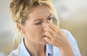 Kvinne med pollenallergi som holder seg på nesen for ikke å nyse