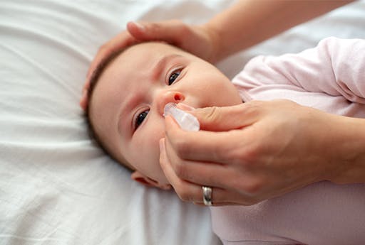 Woman hands with nasal drops and a baby