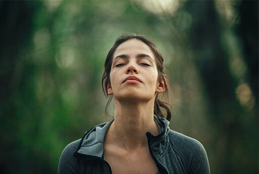 Woman breathes freely в forest with decongested nose.