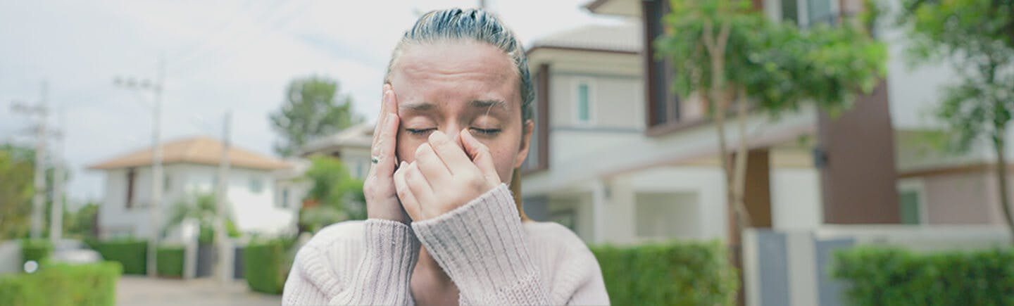 Молодая женщина страдает от последствий загрязнения воздуха, которые включают раздражение дыхательных путей, заложенность носа, обострение респираторных заболеваний и раздражение глаз.