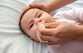 Woman hands with nasal drops and a baby