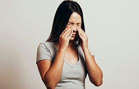 Женщина трет нос из-за синусита, воспаления, которое обычно возникает при простуде.