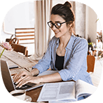 Young woman working from home on her laptop with a book out
