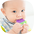 Little baby smiling and biting down on a teether