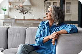 Senior woman sitting relaxed on couch gazing across the room