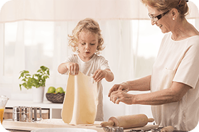 Grandmother and grandchild making dough in the kitchen