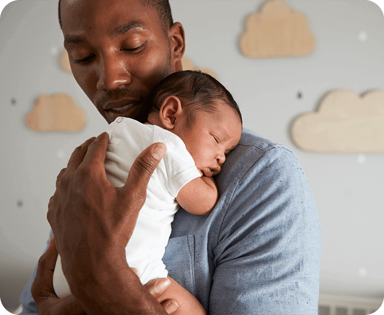 Father holding his new born baby in his arms in the nursery room