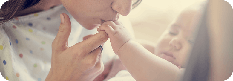Mother kissing the hand of her new born baby