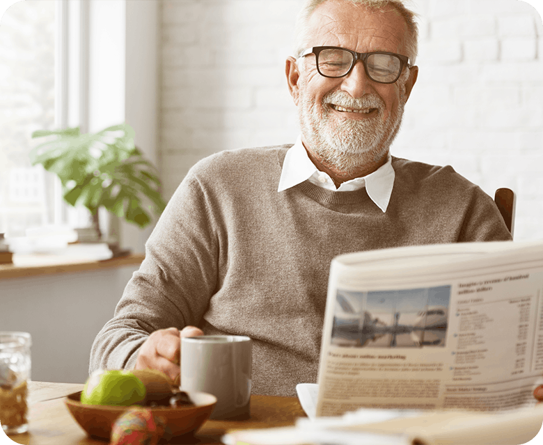 Grandfather reading the newspaper at home with a cup of coffee in hand