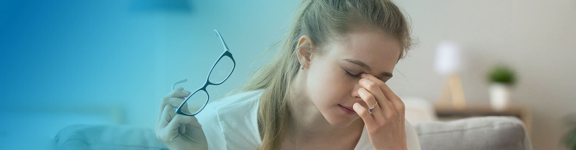 Young woman taking off her glasses and grabbing her nose in pain. 