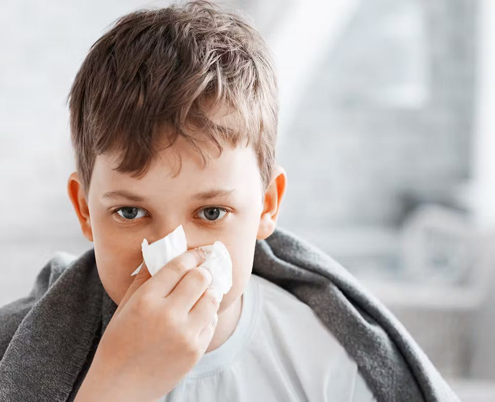 Niño limpiando su nariz con pañuelos desechables.