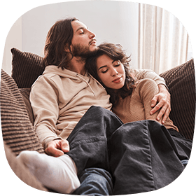 Man and woman sitting on the couch cuddling