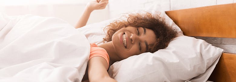 Woman in bed waking up smiling