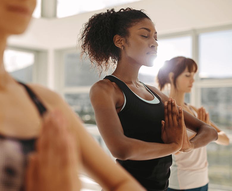 Woman holding her hands in a prayer in a yoga class