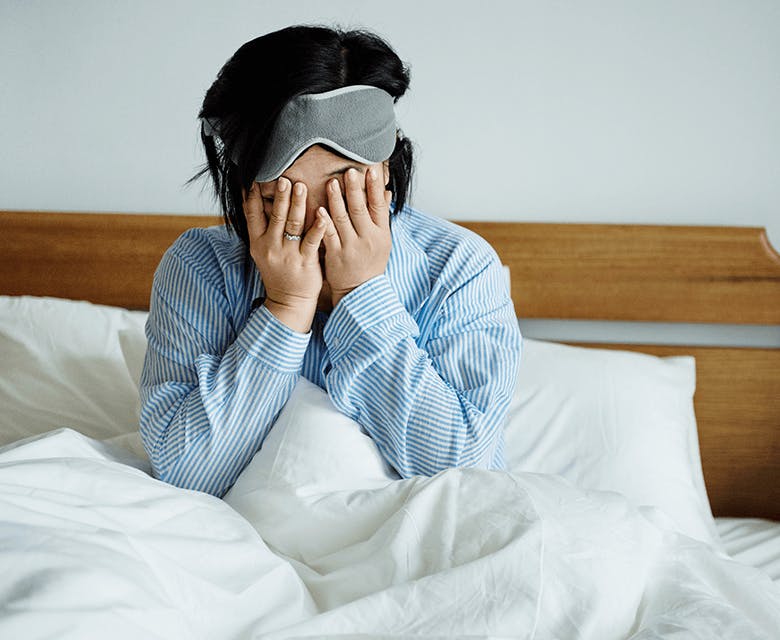 Woman in bed holding her face in pain