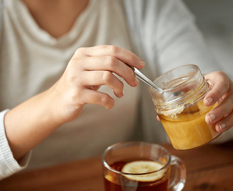 Woman adding honey to her tea