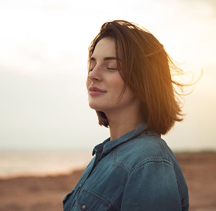Woman standing outside relaxing with her eyes closed