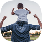 Son sitting on father's shoulders having fun outdoors
