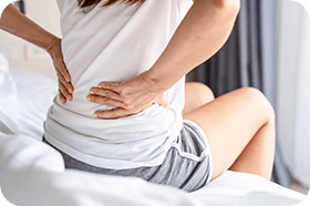 Woman suffering from backache sitting on the bed