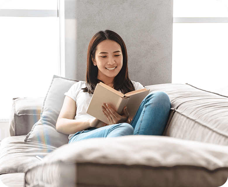 smiling Asian woman reading a book at home
