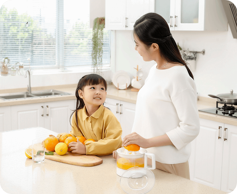 Asian mom and daughter in the kitchen making orange juice