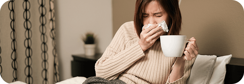 Woman With Flu Symptoms Blowing Nose