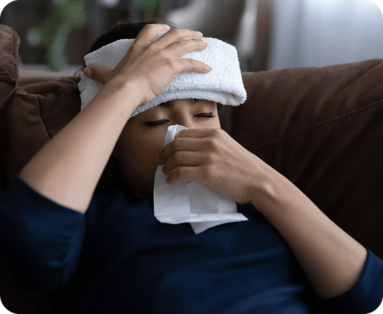 Person With Flu Symptoms Blowing Nose And Reducing Fever With Wet Towel