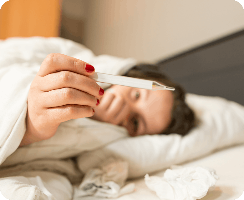 Sick Woman With A Fever In Bed Taking Her Temperature 