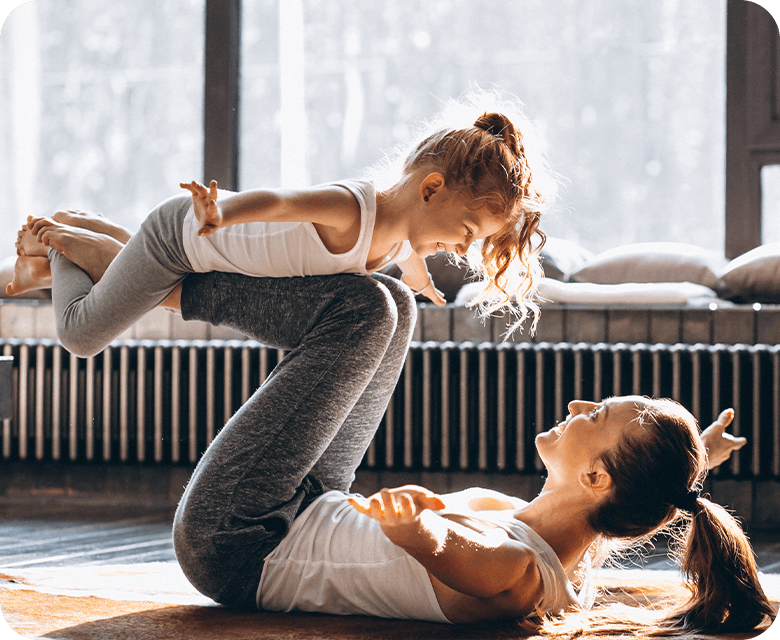Mother performing yoga with her young daughter at home