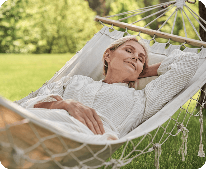 Smiling woman laying on a bed outside on the grass