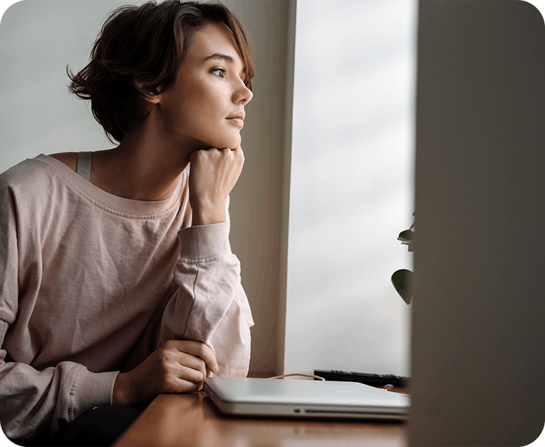Young woman sitting at a desk gazing out the window