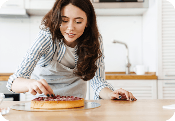 Young woman in the kitchen wearing an apron baking a cake