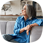Senior woman sitting relaxed on couch gazing across the room