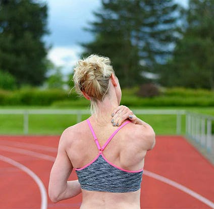 Mujer deportista se toca el homoplato en señal de dolor.