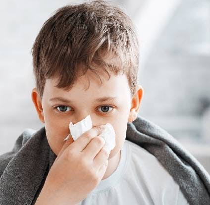 Niño limpiando su nariz con pañuelos desechables. 