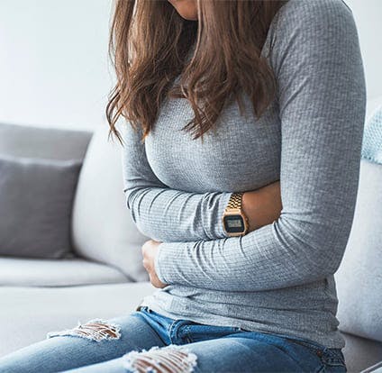 Mujer sujentando con dolor su adbomen.