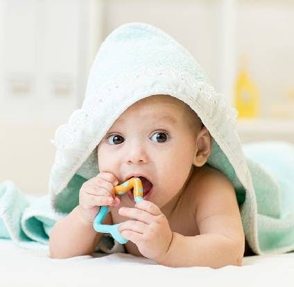 Bebé mordiando un juguete para dentición después de un baño.  