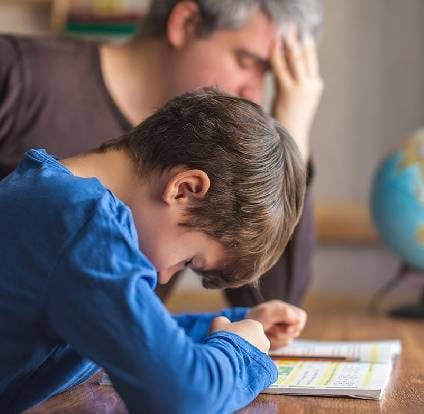 Niño estudiando junto a su padre, con signos de dolor. 