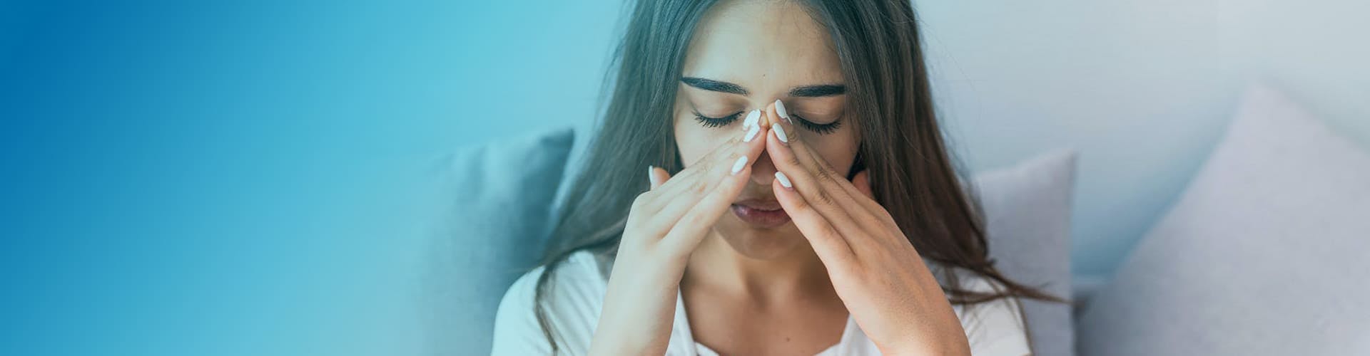 Mujer joven tocándose la nariz en señal de dolor.